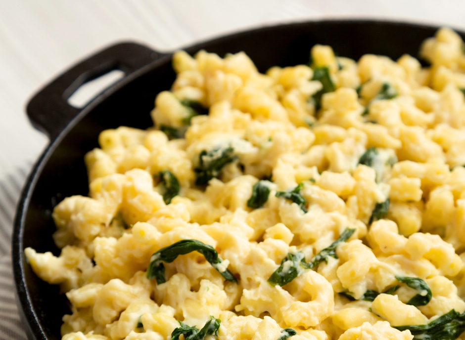 A skillet filled with macaroni and spinach.