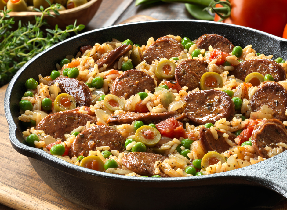 A skillet filled with rice, sausage and peas.