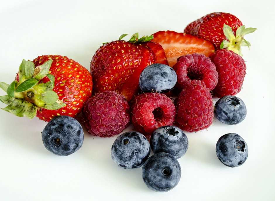 A white plate with strawberries, blueberries and raspberries.