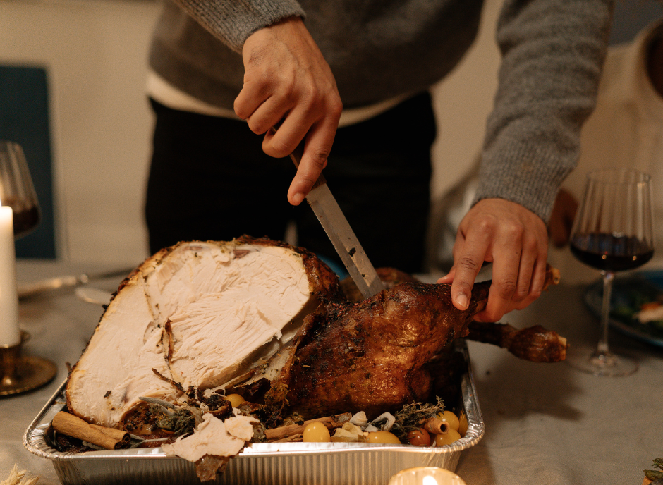 A person skillfully carving a succulent turkey on a table.