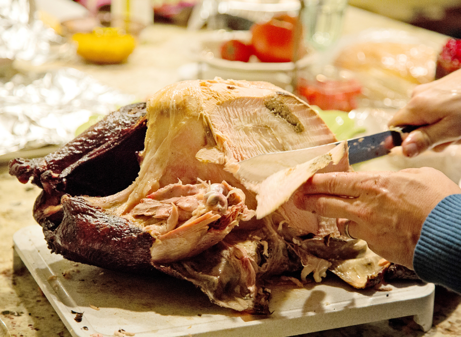 A person is slicing a turkey with a knife to prepare a delicious meal.