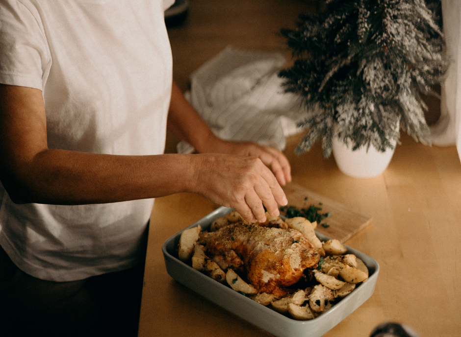 A woman arranging potatoes on a tray with a festive Christmas tree in the background.
