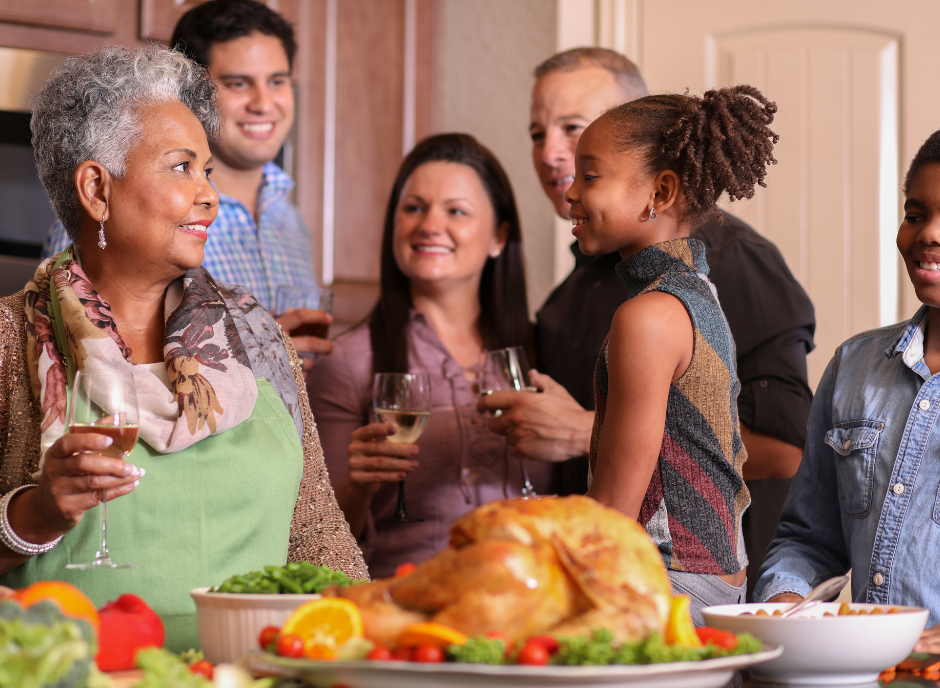 A group of people gathered around a turkey in the kitchen.