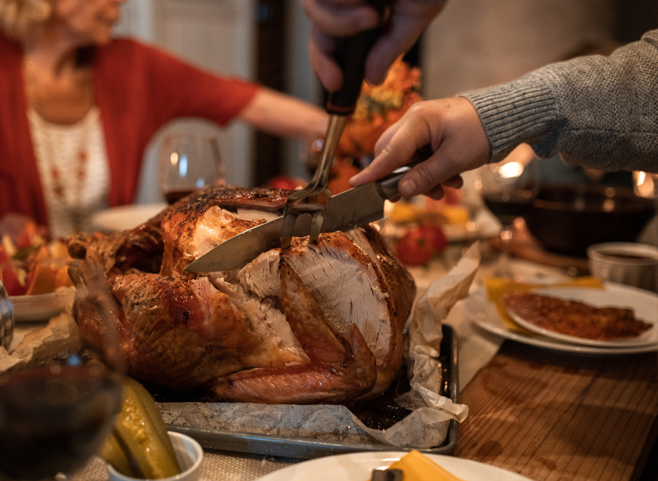 A person cutting a turkey on a table.