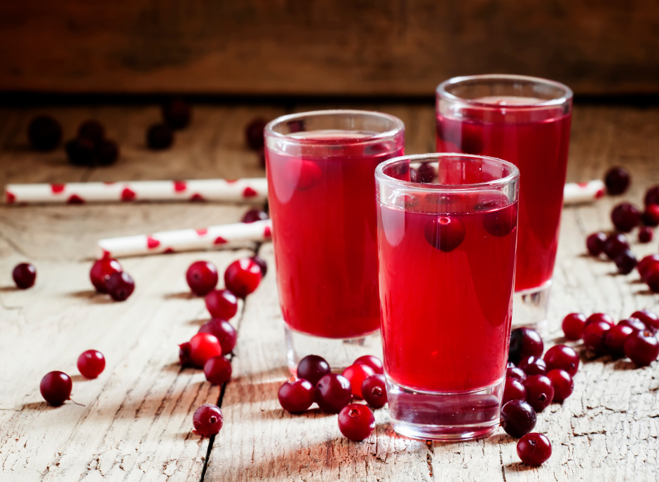 Three glasses of cranberry juice on a wooden table.