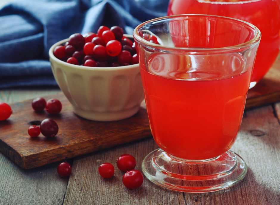 A glass of cranberry juice next to a bowl of cranberries.