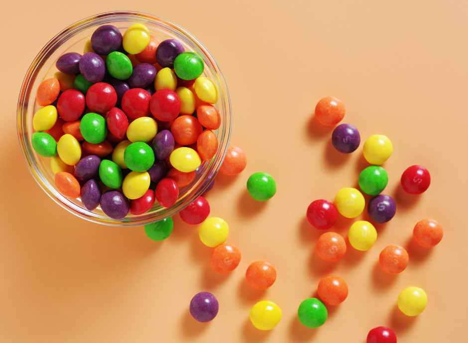Colorful candy in a bowl on an orange background.