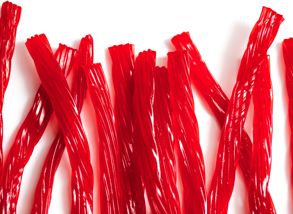 A bunch of red licorice sticks on a white surface.