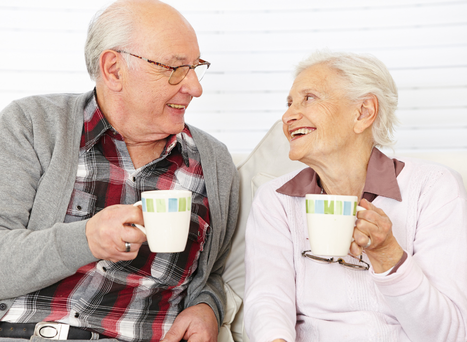 An older couple sipping from coffee mugs while enjoying kidney friendly candy.