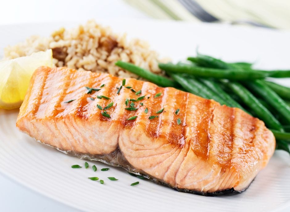Grilled salmon on a plate with green beans and rice.