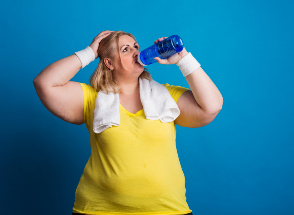A woman drinking water from a bottle on a blue background.