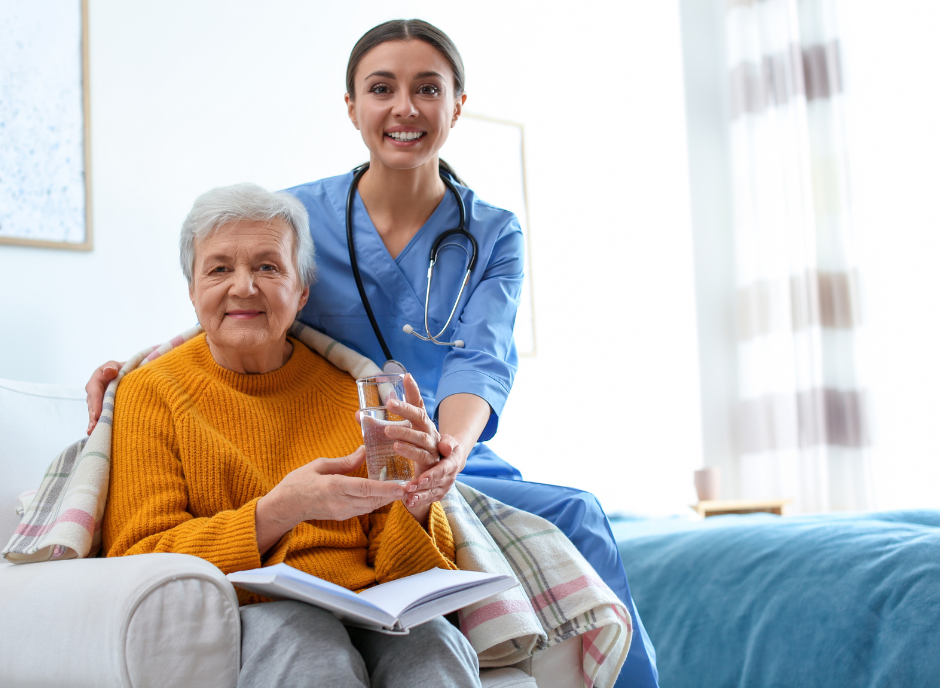 A nurse is sitting with an elderly woman on a couch.