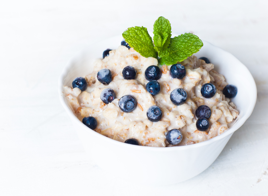 Oatmeal with blueberries and mint in a white bowl.