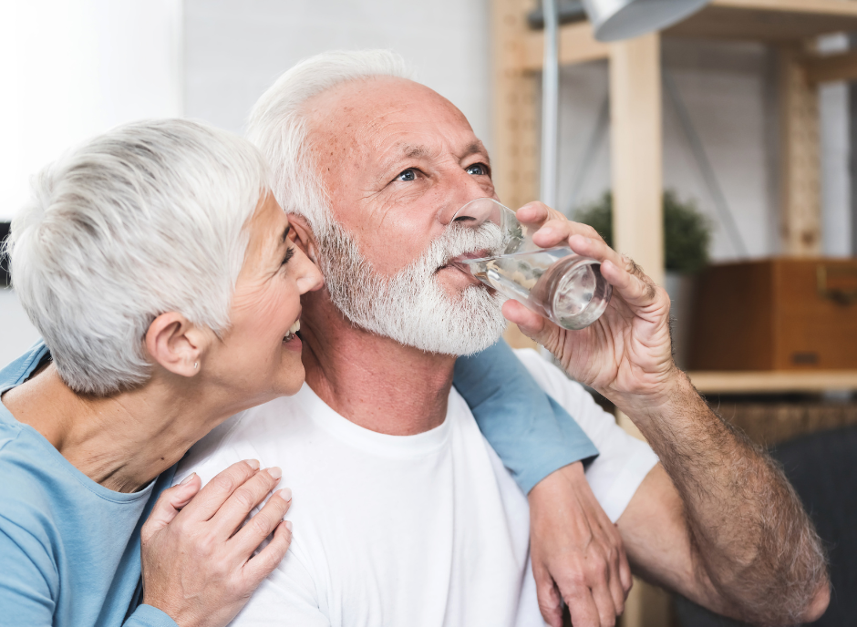 An older couple drinking water from a glass.
