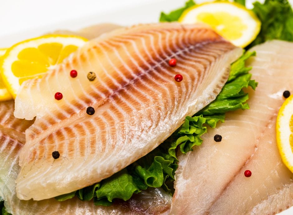 Fish fillets on a plate with lemon slices.