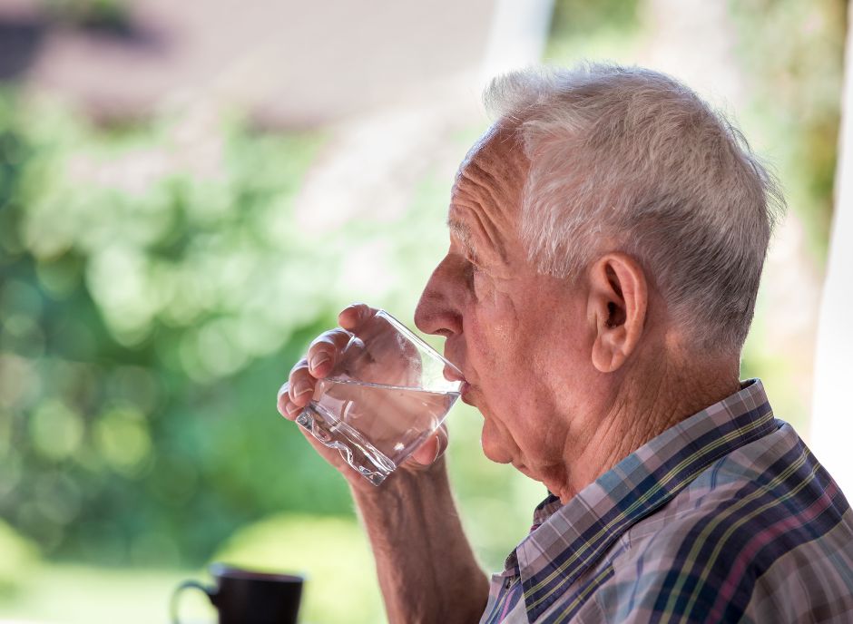 An older man drinking water from a glass.