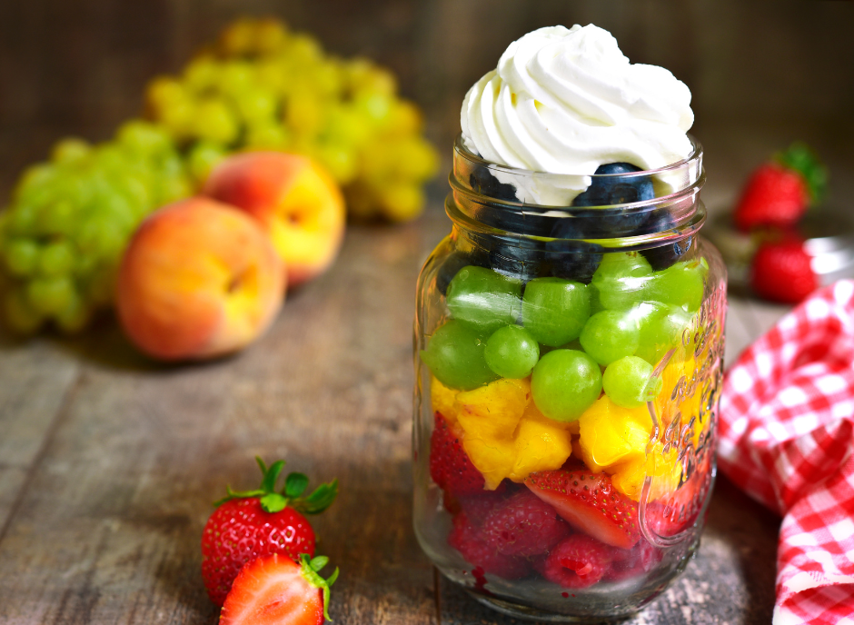 A mason jar filled with fruit and whipped cream.