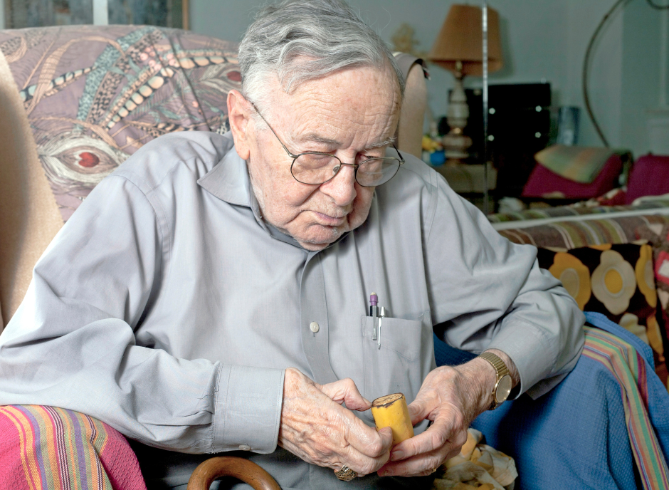 An older man sitting in a chair holding a teddy bear.