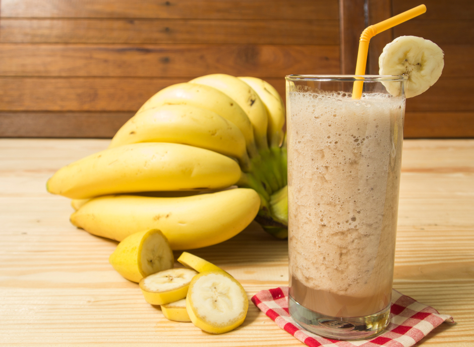 A banana smoothie with a straw on a wooden table.