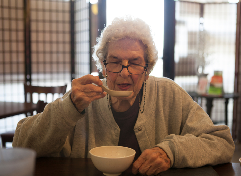 A woman eating a bowl of soup.