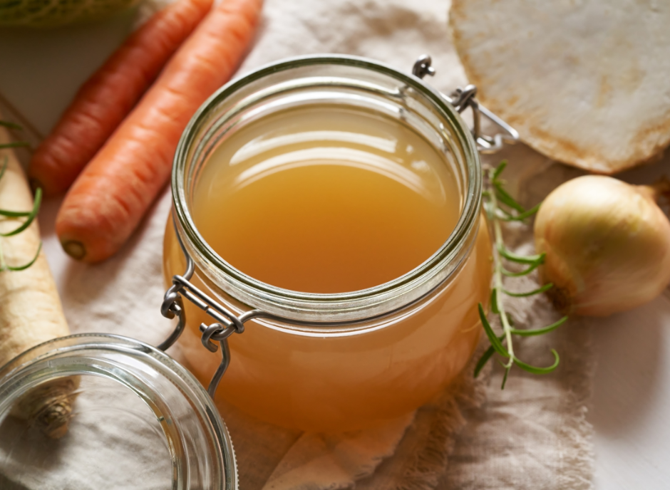 A jar of broth with carrots and onions.