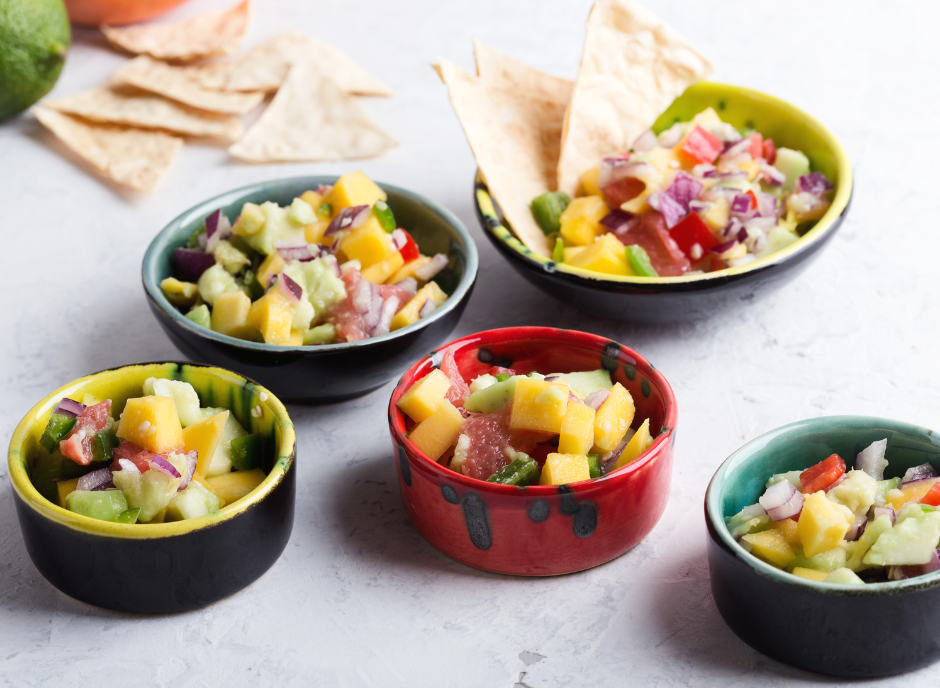Four bowls of mango salsa with tortilla chips.