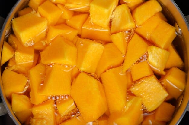 Chunks of ripe mango submerged in liquid inside a pot.