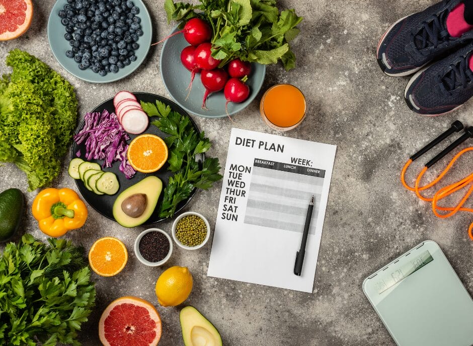 Healthy food, a diet plan, pen, and exercise equipment are displayed on a table, including fruits, vegetables, sneakers, and a jump rope.