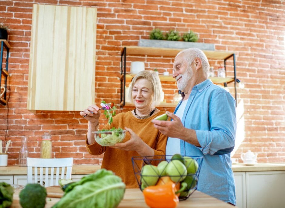 Elderly couple smiling while preparing a salad in a kitchen : foods that help kidney function