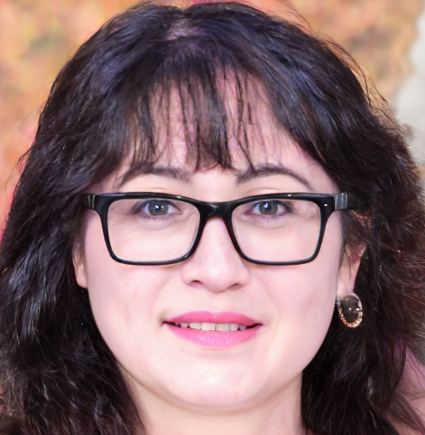 A woman with long dark hair, wearing glasses, and a pair of loop earrings, smiles at the camera.